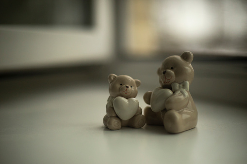 Porcelain toys in room. Cute bears with hearts in their paws. Figurines for decoration. Glass toys.