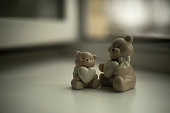 Porcelain toys in room. Cute bears with hearts in their paws. Figurines for decoration.