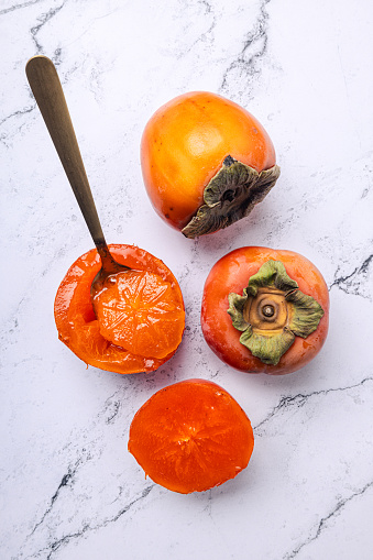 Ripe persimmon fruits or kaki fruits with kaki slices isolated on white background.
