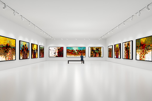 In an art center, visitor looks at the artist's collection.  Modern colorful paintings on exhibition.