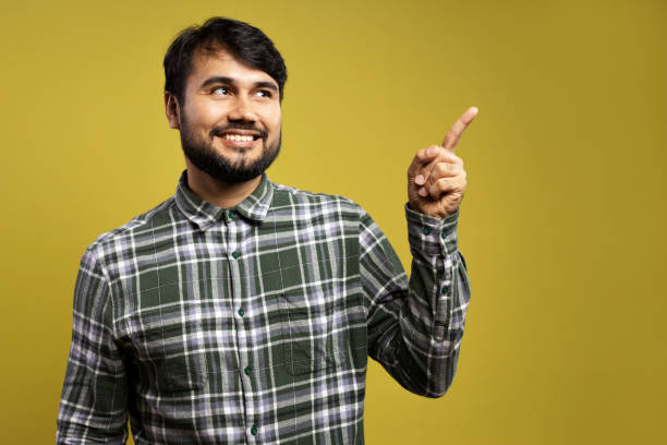 istock man smiling, pointing to the side and looking to the side 1854861248