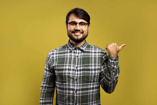 istock man smiling and pointing to the side with his thumb 1854871498