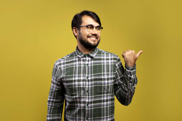 istock man smiling, looking to the side and pointing with thumb 1854871501
