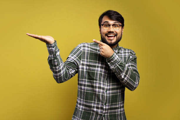 istock man smiling with one hand outstretched and the other pointing 1854872016