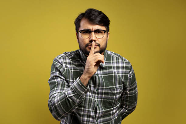istock man asking for silence with his index finger 1854873081