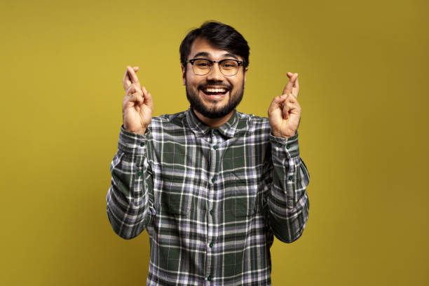 istock man smiling and crossing his fingers 1854874654