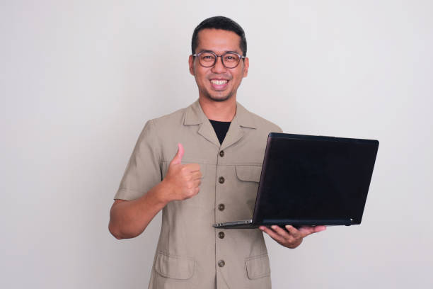 istock Indonesia government worker smiling and giving thumb up while holding a laptop 1854886982