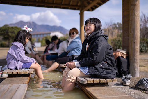 Asian Chinese kids soaking feet enjoying footbath in Kagoshima natural park