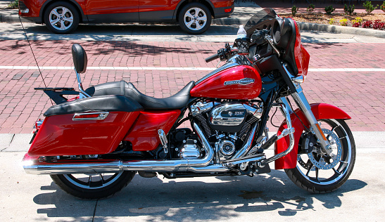 Florida, USA - 1 July 2023: A red motorcycle parked on a sidewalk in Florida.