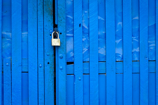 Padlock on blue wooden gate forming a textured background.