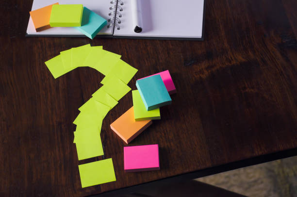 istock High angle view of question mark of sticky notes with notebook and multi colored sticky notes for organizing and productivity 1854943356