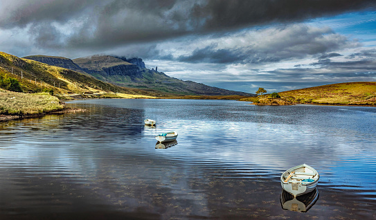 landscape view showing rowing boats on Loch Fada, Isle of Skye, Scotland; the 'Old Man of Storr' can be seen in the distance high on the hillside