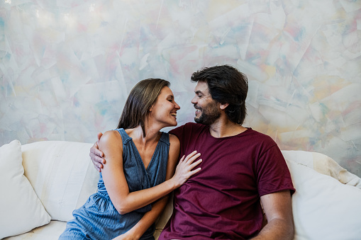 Mid adult couple embracing on sofa at home
