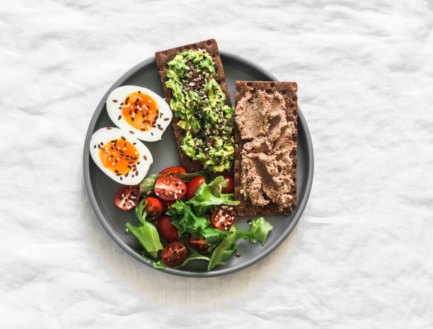 Delicious breakfast, tapas, snack - crispy rye bread crackers with turkey liver, avocado, boiled egg and cherry tomatoes on a light background, top view Delicious breakfast, tapas, snack - crispy rye bread crackers with turkey liver, avocado, boiled egg and cherry tomatoes on a light background, top view egg cherry tomato rye stock pictures, royalty-free photos & images