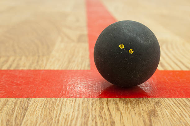 Double yellow dot squash ball on t-line. Double yellow dot official black squash ball on the red t-line in squash court squash sport stock pictures, royalty-free photos & images