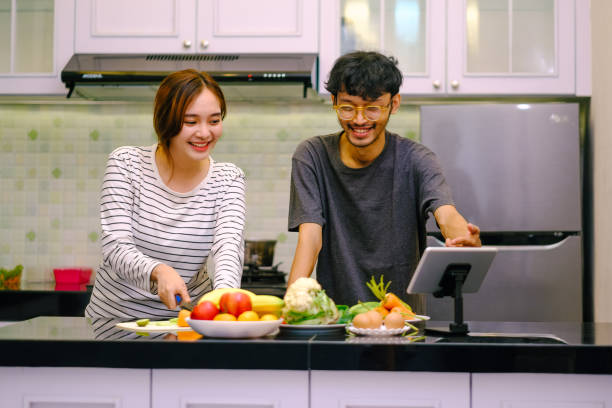 istock Happy Asian Couple Cooking Together Using Digital Tablet. 1854991555