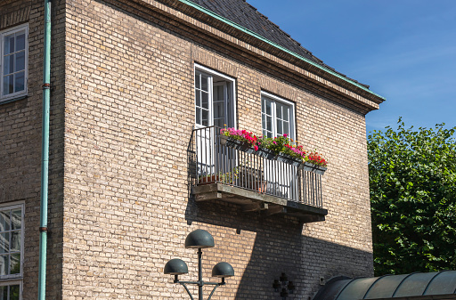 Cozy balcony with flowers in a brick house.