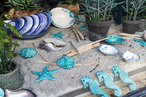 Shop window with ceramics on the sand. Ceramics on a marine theme, plates, shells and sea turtles.