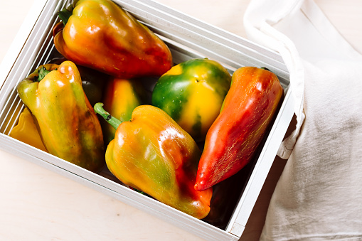 Freshly harvested sweet peppers in a white wooden box.
