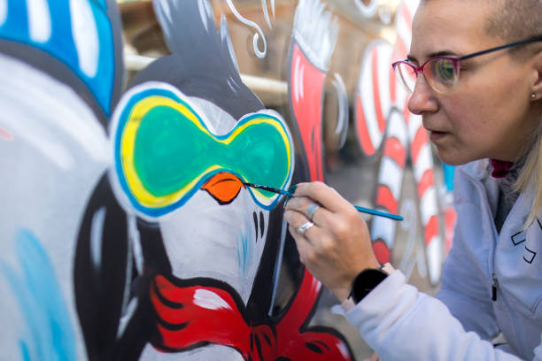The artist uses paint to decorate the shop window for the winter Christmas season.