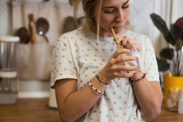 istock A woman drinks water with ice. She uses a drinking straw and tests whether her teeth will react to the cold 1855039333