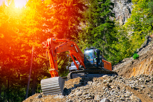 Excavator at the construction site on the slope of a hill against the sunset.