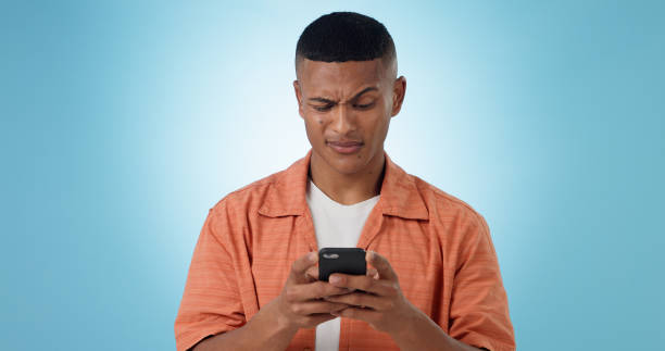 istock Expression, confused and man with a smartphone, typing and connection on a blue background. Person, guy and model with a cellphone, mobile user and reaction with doubt, error 404 and contact with app 1855093962