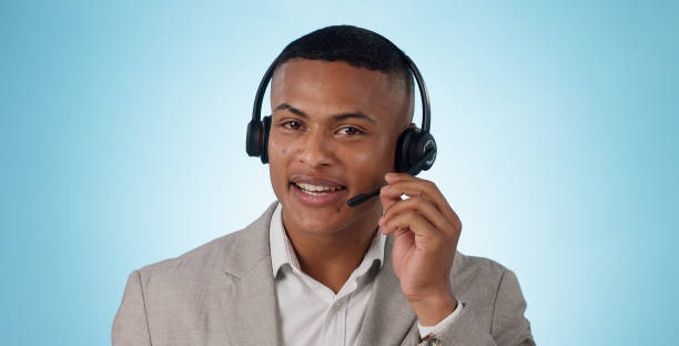 istock Call center, man and portrait in studio for customer service, CRM questions and IT support on blue background. Face of telemarketing salesman, virtual consultant and microphone for telecom advisory 1855095053