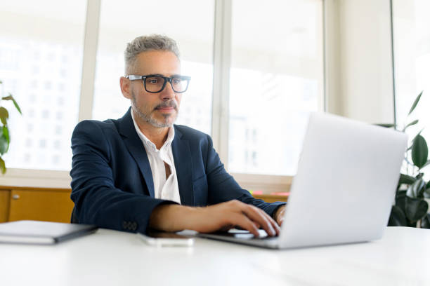 istock Smiling optimistic mature gray-haired businessman ceo wearing eyeglasses using laptop 1855112744