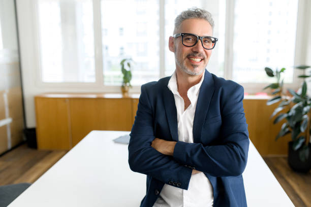 Mature male employee standing with arms crossed Headshot of high-skilled mature male employee standing with arms crossed in modern office, successful confident 50s businessman wearing eyeglasses, business portrait of senior 60s entrepreneur old rich white guy stock pictures, royalty-free photos & images