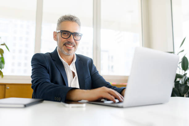 istock Smiling optimistic mature gray-haired businessman ceo wearing eyeglasses using laptop 1855113257