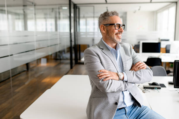 Mature male employee Successful authoritative confident mature grey-haired adult male entrepreneur businessman professional in formal wear standing at the modern home office, looking at camera old rich white guy stock pictures, royalty-free photos & images