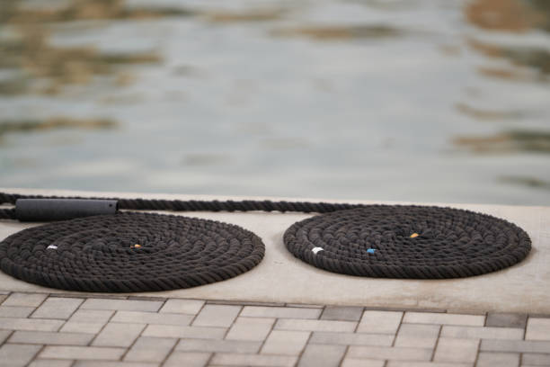 Mooring rope coiled on dockside, with blurred water background.