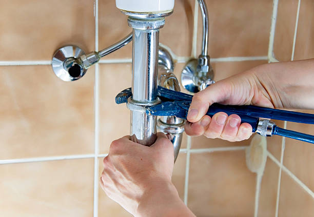 istock Plumber's hands with a blue wrench working on a sink's pipes 185511850