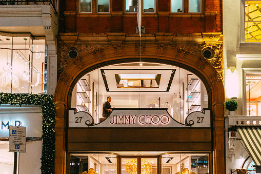 London, UK - 11 December, 2023: exterior architecture and storefront of the Jimmy Choo store in New Bond Street in central London, UK. The store is illuminated at night.