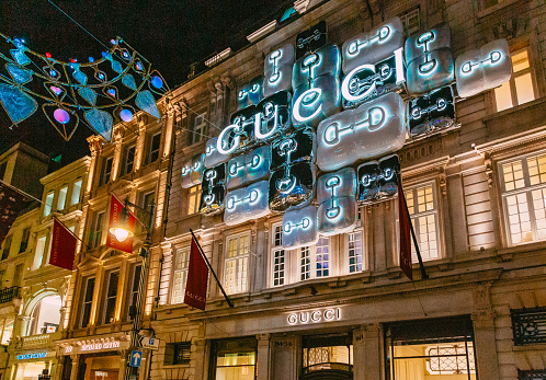 London, UK - 11 December, 2023: exterior architecture and storefront of the Gucci store in New Bond Street in central London, UK. The store is illuminated at night.