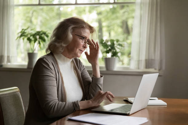 istock Pensive aged female pensioner work by laptop computer from home 1855138838