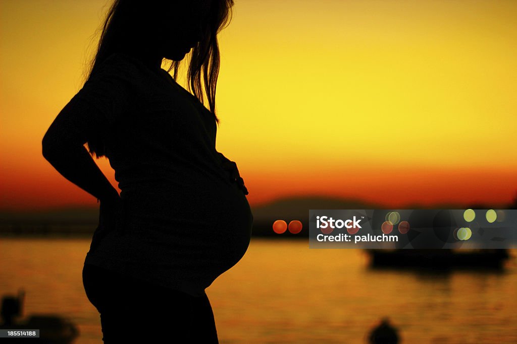 Silueta de una mujer embarazada en la puesta de sol - Foto de stock de Embarazada libre de derechos