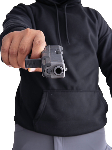 Unidentified male criminal wearing a black hoodie and covering his face, holding a pistol and aiming. On a white background with cliping path. thief.weapon, crime.burglar,cat paw,burglar