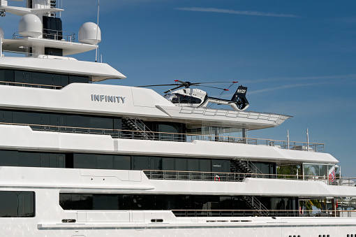 Miami, Florida, USA - 5 December 2023: Luxury super yacht Infinity in Miami with a helicopter (registration N11ZF) on the top deck.