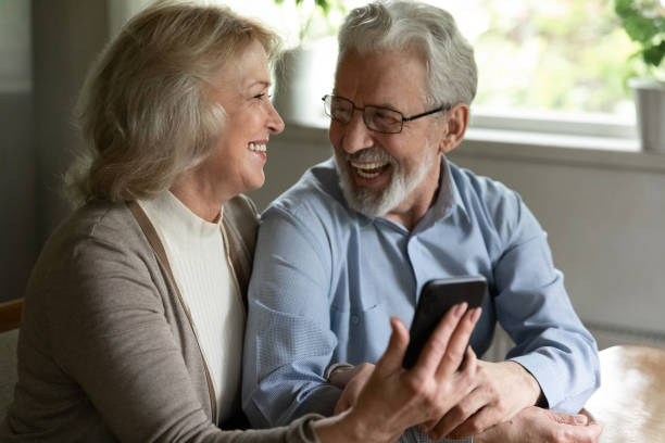 istock Joyful older spouses embrace relax with cell discuss funny video 1855167821