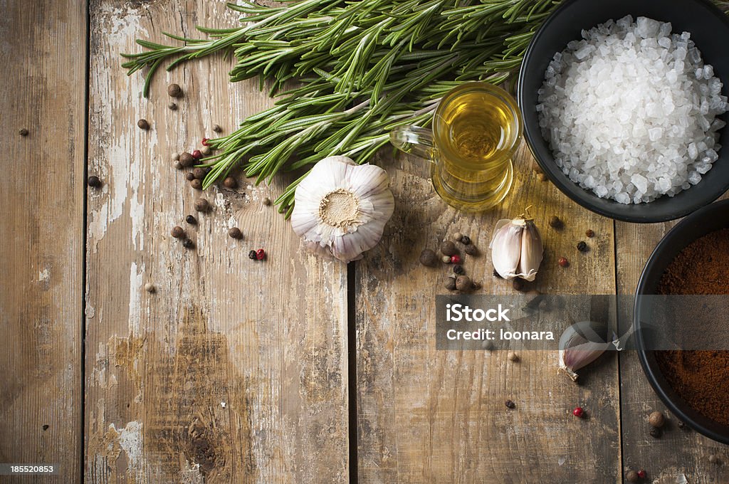 rustic kitchen background Different spices, rosemary, allspice, garlic, oil and salt on a wooden board, rustic kitchen background Backgrounds Stock Photo