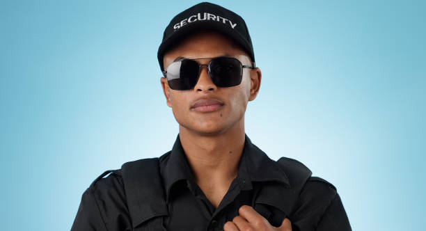 istock Security guard, portrait and man in studio with glasses for surveillance, justice and law enforcement on blue background. Serious bodyguard for crime prevention, safety patrol and monitoring danger 1855219906
