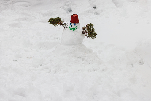 Delightful and whimsical of a snowman crafted by a child in the garden on a frosty winter day.