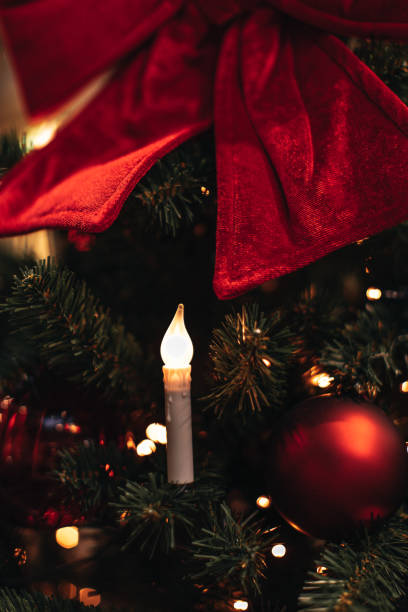 бархатный красный бант, рождественский шар и свеча, висящая на елке. - bow christmas red velvet стоковые фото и изображения