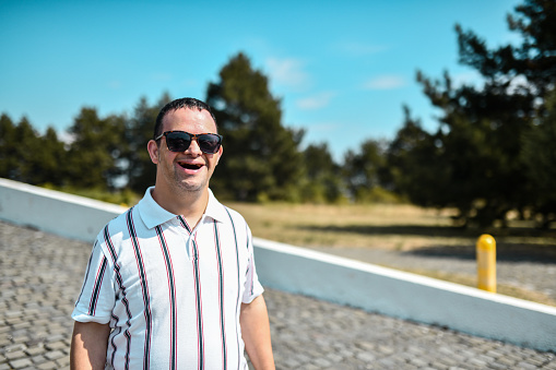 Portrait Of Smiling Male With Down Syndrome Wearing Sunglasses Outside
