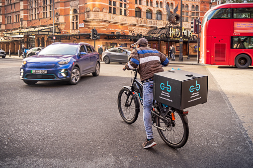 Bedford Court, London, England - October 30th 2023:  Man on a bike from a food delivery service in a street intersection