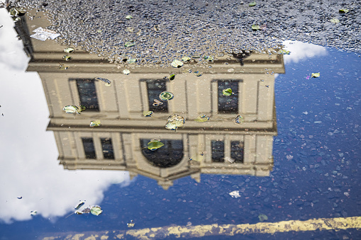 William IV Street, London, England - October 30th 2023:  Classic English building mirrored in a puddle in the center of the British capital