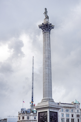 Trafalgar Square, London, England - October 30th 2023:  The famous statue of admiral Nelson and a construction crane against a cloudy sky