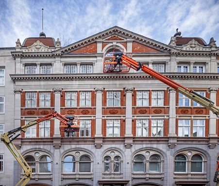 Drury Lane, London, England - October 30th 2023:  Two construction lifts working on a facade of a classic English building